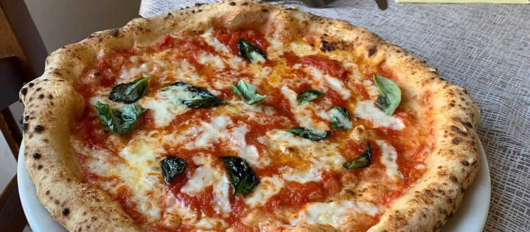 Think of a sun-drenched terrace where the smell of freshly baked, bubbly pizza fills the air—where does this classic slice call home?